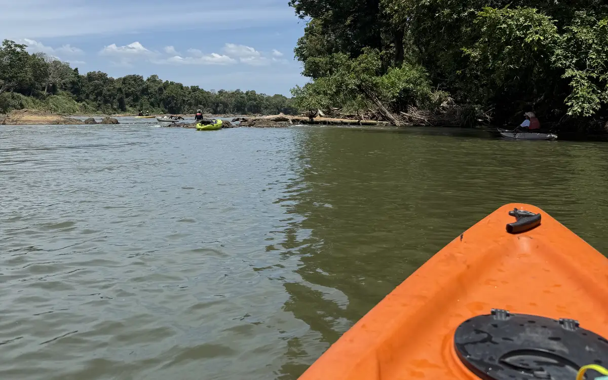 Kayaks on the Mahaweli river, seen over the bow of an orange kayak