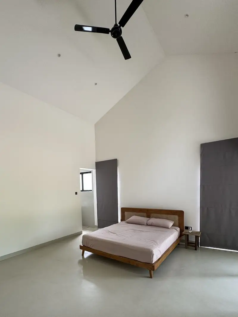 The room: vaulted white ceiling, polished titanium-finish floor, one bed